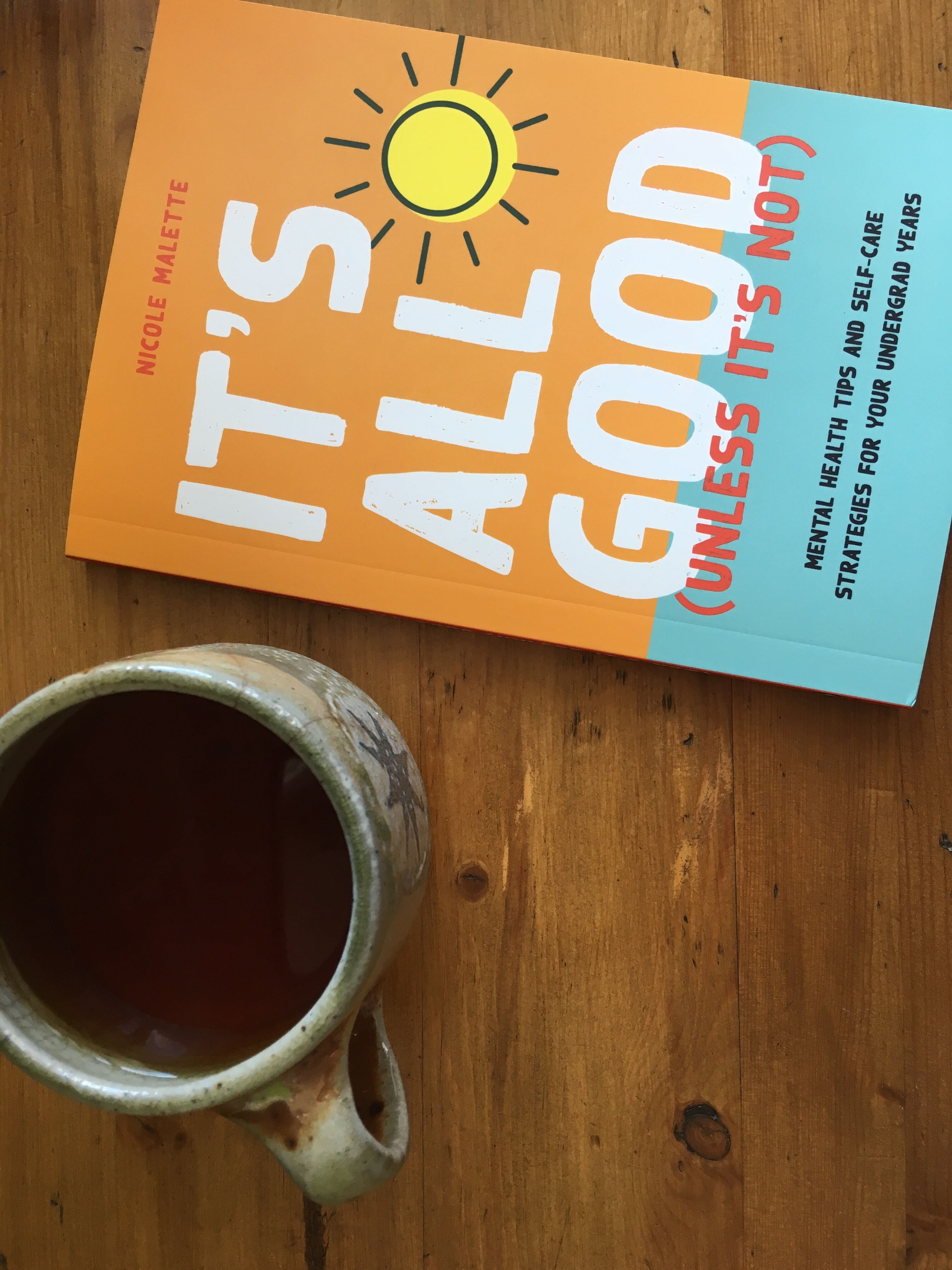 It''s All Good sitting on a table with a cup of copy in a grey ceramic mug